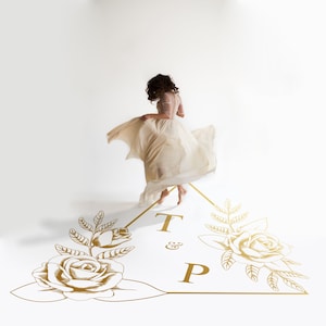 May include: A woman in a white dress spins on a white background with a gold triangle design featuring two roses and the text "T & P".