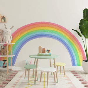 May include: A colorful rainbow wall decal in a children's playroom with a green table and chairs, a wooden shelf with toys, and a potted plant.