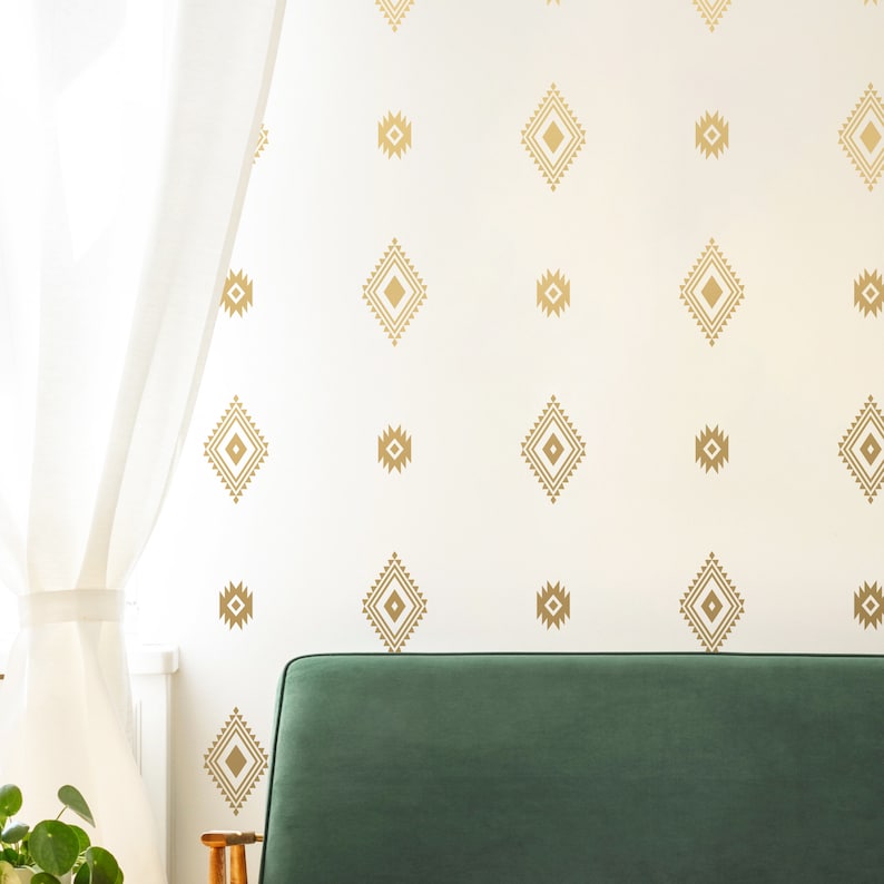 May include: A white wall with a gold geometric pattern of repeating diamond shapes. A green sofa is in the foreground.