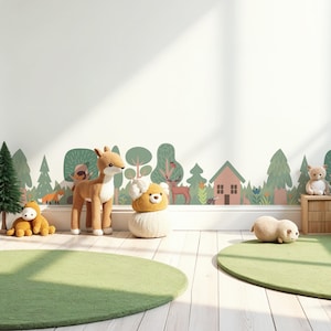 May include: A children's playroom with a green and brown woodland animal wall decal. The decal features trees, a house, a deer, a fox, and other woodland creatures. There are two green and brown plush toys on the floor, a deer plush toy, and a bear plush toy.