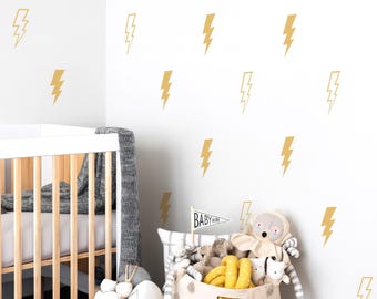 May include: A nursery scene with a white crib and a wall decorated with gold lightning bolt decals. A basket and a fabric bin are filled with stuffed animals and toys. A small flag reads "BABY".