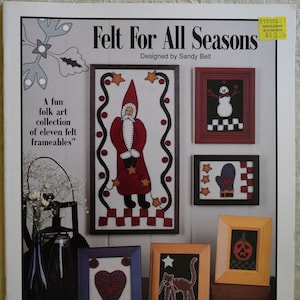 May include: A book cover with the title "Felt For All Seasons" designed by Sandy Belt. The cover features a variety of felt crafts, including a snowman, a Santa Claus, a heart, a cat, and a pumpkin. The book is published by Indygo Junction, Inc.