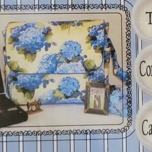 May include: A blue and white floral print fabric computer carry all bag with a small picture frame and a miniature sewing machine. The bag has a strap and a flap closure. The text "The Computer Carry All" is visible on the image.