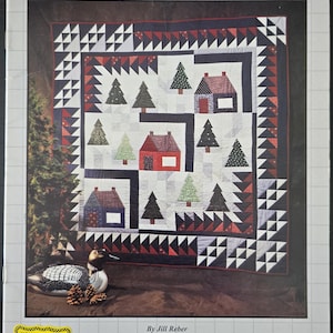 May include: A quilt pattern featuring a winter scene with houses and trees. The quilt is made up of black, white, red, and blue fabric. The title of the pattern is "North Wind Doth Blow".