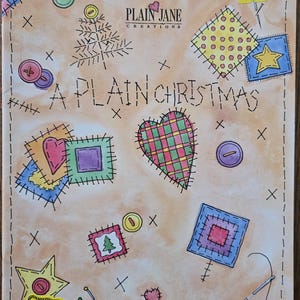 May include: A beige background with a patchwork design featuring hearts, stars, and a Christmas tree. The text "A PLAIN CHRISTMAS" is written in black with a stitched border. The text "PLAIN JANE CREATIONS" is written in black with a red heart.