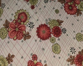 May include: A pink fabric with a repeating pattern of red, green, and white flowers. The flowers are stylized and have a retro look.