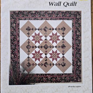 May include: A quilting pattern for a Star Flower wall quilt, measuring 69 inches square. The pattern features a star design with a brown, beige, and pink color scheme. The pattern is by Thimbleberries, by Lynette Jensen.