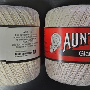 May include: Two spools of off-white Aunt Lydia's Giant Crochet thread. The labels read "ART. 150" and "400 YDS." One label is red with the brand name and a vintage illustration. The other label includes a barcode and text about the thread's use.