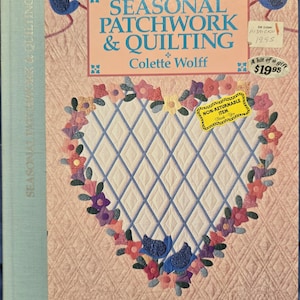 May include: A book titled "Seasonal Patchwork & Quilting" by Colette Wolff. The cover features a heart-shaped quilt with a blue and white diamond pattern surrounded by a border of colorful flowers and birds.