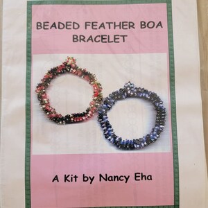 May include: A beaded feather boa bracelet kit by Nancy Eha. The kit includes two bracelets, one in red, black, and white beads and the other in blue, black, and white beads. The kit is easy to learn and costs $35.