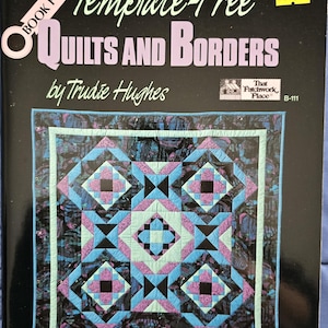 May include: Book cover for "Template-Free Quilts and Borders" by Trudie Hughes. The cover features a colorful quilt with a geometric pattern in shades of blue, pink, black, and white.