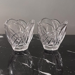 Puede incluir: Dos cuencos decorativos de vidrio transparente con un diseño en forma de pétalo. Los cuencos tienen un aspecto texturizado de vidrio tallado y se asientan sobre una superficie oscura y reflectante. Los cuencos están vacíos y parecen estar en excelentes condiciones.