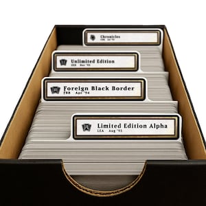May include: A black storage box filled with stacks of trading cards separated by white dividers. The dividers feature labels for Limited Edition Alpha, Foreign Black Border, Unlimited Edition, and Chronicles, each with specific set codes and dates.
