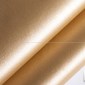 May include: Close-up of a gold-colored leather fabric with a textured surface. The fabric is folded in half, and the label #44A is visible in the lower right corner.