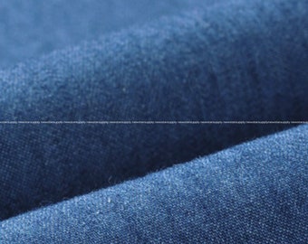 May include: Close-up of a textured, dark blue fabric. The image shows the folds and details of the material, with a focus on the weave and color variations. The fabric appears to be a medium-weight material, possibly denim or a similar textile.