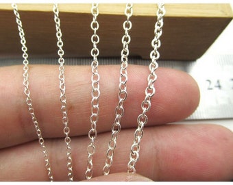 May include: Close-up of several silver-colored chain necklaces with varying link sizes. The chains are displayed against a neutral background, showcasing their reflective qualities. The image highlights the different chain styles.