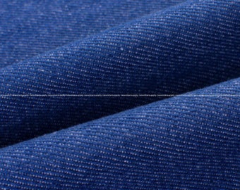 May include: Close-up of blue denim fabric. The fabric is folded, showing the texture and weave of the material. The color is a deep, saturated blue, with subtle variations in tone. This image is suitable for apparel or textile-related listings.