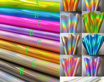 Op de afbeelding: Tien rollen iriserende holografische vinyl in verschillende kleuren, waaronder groen, blauw, roze, paars, goud en zilver. De vinyl wordt gerold en plat gevouwen getoond.