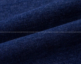 May include: Close-up of dark blue denim fabric with visible texture and subtle folds. The fabric appears to be a medium weight, suitable for various apparel items. The image highlights the weave and color variations.