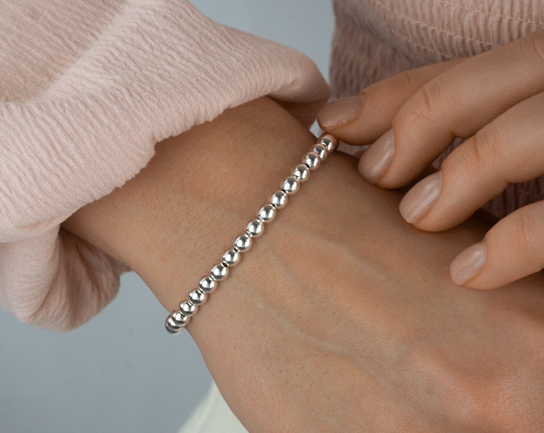 K&ouml;nnte beinhalten: Ein silbernes Armband mit einem schlichten Design. Das Armband besteht aus kleinen, runden Perlen, die gleichm&auml;&szlig;ig verteilt sind.
