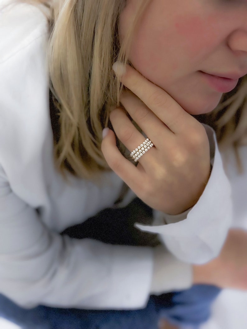 May include: A silver ring with multiple rows of small, round beads.