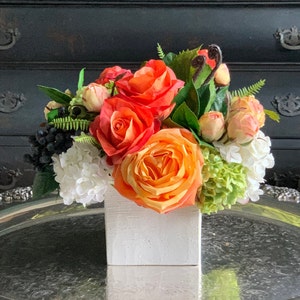 Lush faux arrangement in vibrant tones orange roses peach viburnum and berries in white ceramic vessel [Home Decor] Centerpiece [Staging]