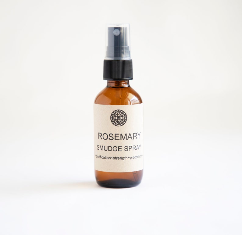 Pu&ograve; includere: Un flacone spray in vetro ambrato con erogatore in plastica nera ed etichetta beige. L'etichetta presenta un'icona geometrica circolare, il testo ROSEMARY SMUDGE SPRAY e le parole purification~strength~protection stampate in inchiostro nero.