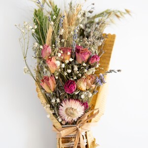 May include: A bouquet of dried flowers wrapped in brown paper with a dried orange slice and cinnamon stick. The bouquet includes pink roses, lavender, and other dried flowers.