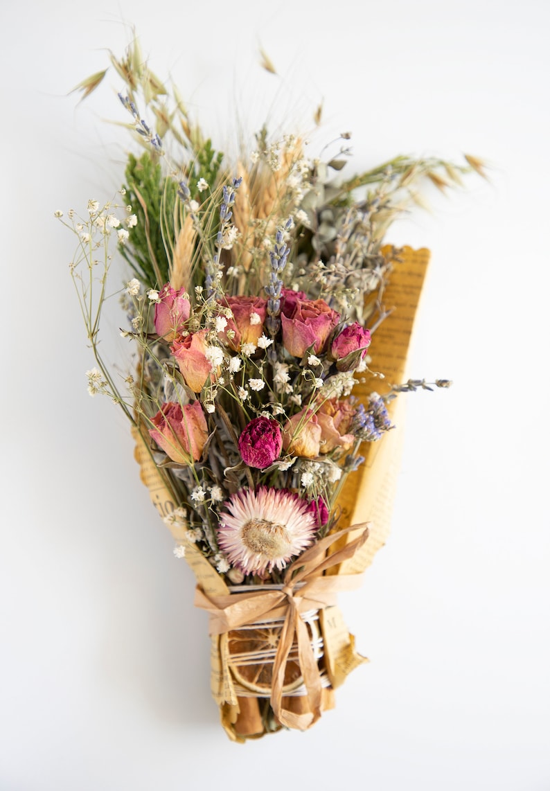 May include: A bouquet of dried flowers wrapped in brown paper with a dried orange slice and cinnamon stick. The bouquet includes pink roses, lavender, and other dried flowers.