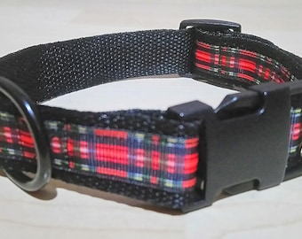 May include: Black dog collar with a red, black, and green plaid pattern. The collar has a black plastic buckle and a metal D-ring for leash attachment. The collar is made of a durable, woven material.