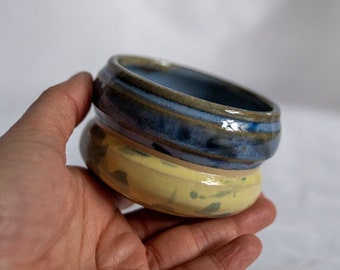 Ceramic stoneware espresso coffee or tea cup colourful glaze design. Yellow and blue splatter half wonky curvy cup