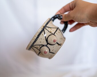 Stoneware ceramic boob mug with strappy harness lingerie in black on spotted clay with handle. Body tit/breast coffee/tea cup