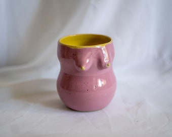 Ceramic stoneware shiny pink coffee or tea cup in female form shape. Boob/breast/tit ceramic glazed pink and glossy yellow inside