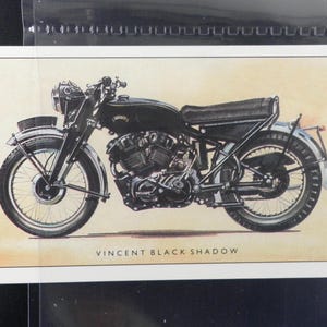 Puede incluir: Ilustraci&oacute;n de una motocicleta negra Vincent Black Shadow. La motocicleta vintage se representa de perfil, mostrando su motor, ruedas y asiento. El texto "VINCENT BLACK SHADOW" est&aacute; impreso debajo.