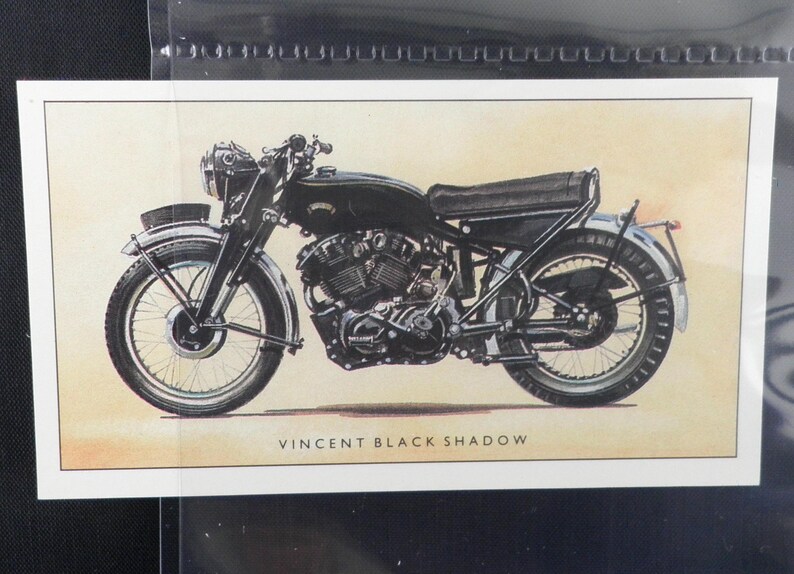 Puede incluir: Ilustraci&oacute;n de una motocicleta negra Vincent Black Shadow. La motocicleta vintage se representa de perfil, mostrando su motor, ruedas y asiento. El texto "VINCENT BLACK SHADOW" est&aacute; impreso debajo.
