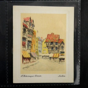 Puede incluir: Una postal vintage que representa un rincón pintoresco de Ludlow, Inglaterra. La postal presenta una ilustración colorida de una calle bordeada de edificios antiguos, incluyendo una casa de entramado de madera con un techo rojo.