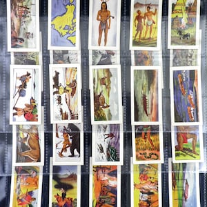Può includere: Una collezione di figurine vintage, ognuna con illustrazioni colorate della vita dei nativi americani, paesaggi e scene storiche. Le carte sono esposte in un foglio di plastica trasparente, mostrando l'opera d'arte e il contesto storico.