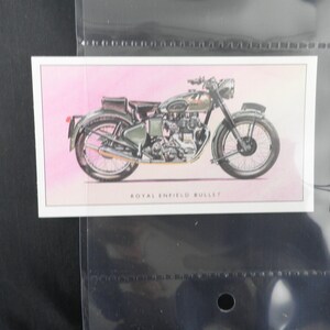 Puede incluir: Ilustraci&oacute;n de una motocicleta Royal Enfield Bullet en una tarjeta. La moto est&aacute; representada en tonos grises y verdes, sobre un fondo rosa. El texto "ROYAL ENFIELD BULLET" est&aacute; impreso debajo de la imagen.