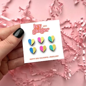 May include: A set of six wooden heart earrings with a gold glitter accent. The hearts are in three colour combinations: blue and yellow, pink and yellow, and teal and yellow. The card reads "ivy and ginger, happy and colourful jewellery".