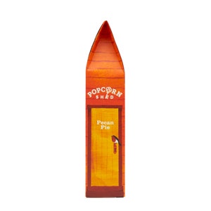 May include: A red and orange box with a yellow door and the text "Popcorn Shed" and "Pecan Pie". A small bird is perched on the door handle.