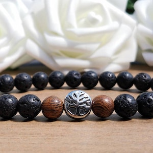 May include: A black lava rock and wood bead bracelet with a silver tree of life charm.