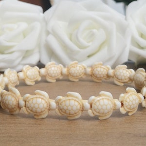 May include: A white beaded bracelet featuring a turtle design. Each bead is a detailed turtle shape.