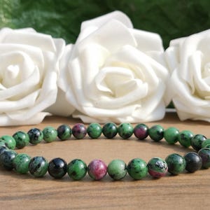 May include: A green and pink gemstone bracelet with round beads. The bracelet is made of natural stones and is a beautiful accessory for any occasion.