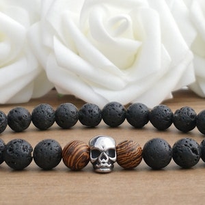 May include: A black lava rock bracelet with wooden beads and a silver skull charm.