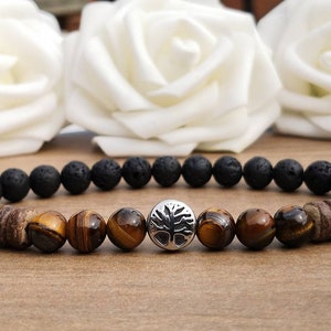 May include: A beaded bracelet featuring black lava rock, tiger's eye beads, and a silver tree of life charm.