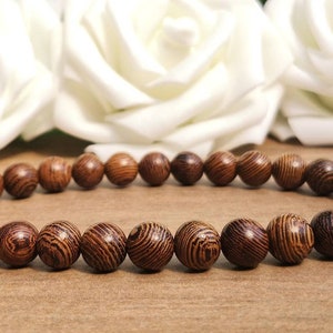 May include: A brown wooden bracelet with round beads. The beads have a striped pattern.