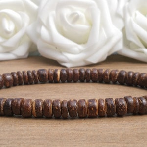 May include: A brown wooden beaded bracelet with a simple design. The bracelet is made of small, round beads that are strung together on a cord.