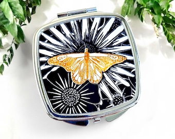 Espejo compacto con diseño de mariposa: con linografía en negro y dorado de una mariposa rodeada de flores. Viene en una caja de regalo. Un regalo ideal para mujeres.