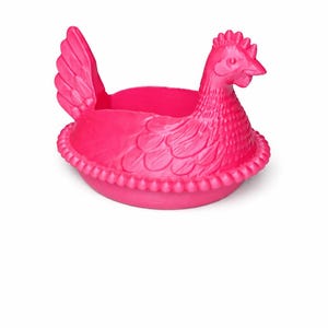May include: A bright pink hen-shaped planter. The planter features a detailed hen with a textured body, a comb, and a beak. The base of the planter has a decorative beaded edge. The hen's wings are visible on the side.