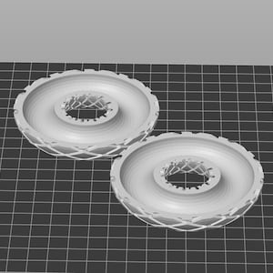 Puede incluir: Dos objetos circulares grises impresos en 3D con un patrón de rejilla texturizado en relieve. Los objetos tienen un agujero central y un anillo circular elevado más pequeño alrededor del agujero.